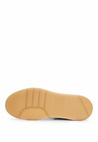 Sole of a shoe with a smooth, beige rubber material. It features horizontal grooves for traction and a subtle logo embossed on the side.