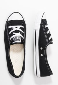 Fekete vászon, alacsony szárú sportcipők fehér gumi orral és talppal, fekete fűzőkkel és kontrasztos varrással. A nyelvén "Converse All Star" logóval rendelkezik.