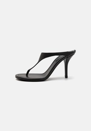 Black high-heeled sandals with a thin strap, thong design, pointed toe, and a sleek, smooth finish. Flat sole with a discreet heel.