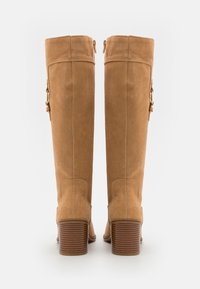 Tan suede knee-high boots with a textured design, featuring a stacked heel and gold-tone hardware accents at the side zippers.