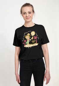 Schwarzes Baumwoll-T-Shirt mit einem bunten Cartoon-Graphic eines Mädchens und einer Sonne mit Text, vor einem hellen Hintergrund.