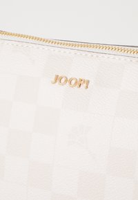 Portafoglio bianco con una superficie texturizzata e a scacchi e una cerniera dorata. Il logo del marchio "JOOP!" è impresso in oro sul davanti.