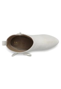 Stivaletto in suede bianco con punta affusolata, fiocco decorativo, zip laterale e interni di colore chiaro con il nome del marchio in lettere dorate.