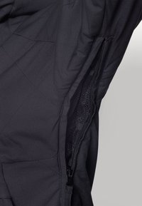 Black quilted fabric featuring a side zip pocket with mesh lining, showcasing a smooth texture and structured design elements.