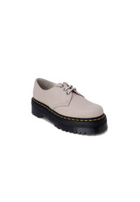 Scarpa stringata in pelle beige con suola in gomma nera spessa e un accento di cucitura gialla. Punta tonda e texture liscia.