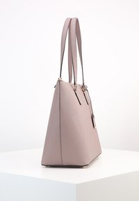 Vaaleanpunainen synteettinen olkalaukku, jossa on jämäkkä, kolmion muotoinen rakenne. Laukussa on kaksi pitkää kahvaa ja kultaiset yksityiskohdat. Pintamateriaali on sileä ja yksityiskohdat ovat vähäiset.