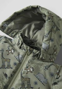 Veste rembourrée de couleur vert olive avec un imprimé animal fantaisiste mettant en scène des girafes, des singes et des ours. Comprend une capuche et un zip à l'avant.