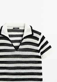 Polo shirt rayé en noir et blanc, avec un col, des manches courtes, et un tissu tricoté texturé avec un design en v.