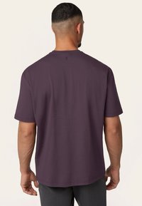 Korte mouw, ronde hals t-shirt van donkerpaars katoen met een gladde textuur. Heeft een klein logo boven de hals aan de achterkant.