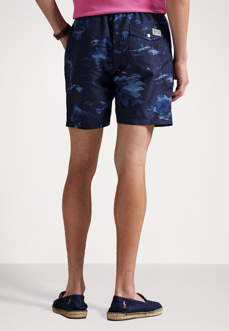 Shorts de bain bleu marine avec un imprimé tropical comprenant des bateaux et des palmiers. Taille élastique avec poche arrière et étiquette de marque.