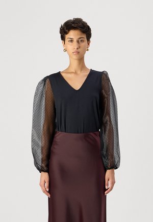 Svart topp med V-hals og gjennomsiktige puff-ermer med prikk mønster, parret med en bordeaux sateng skjørt. Elegant design med myke teksturer.