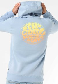 Felpa leggera di colore azzurro con una consistenza morbida. Grafica circolare con sfumature gialle e arancioni sul retro con il testo "RIP CURL WETSUITS".