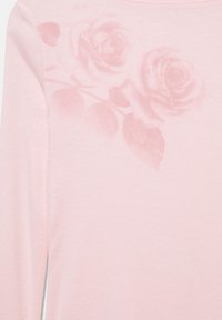 Lyserød langærmet skjorte med et subtilt mønster af mørkere lyserøde roser og blade nær halsudskæringen foran.