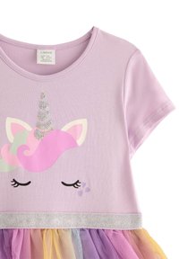 Lila bomullstopp med enhörningsmotiv, prydd med paljettaccenter. Tyllkjol i gradientfärger av lila, rosa och gult, med silvrig kant.