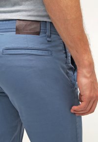 Blå bomullsshorts med en mjuk textur, med en bakficka och en brun läderlapp märkt "BOSS ORANGE."