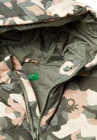 Giacca imbottita con un motivo mimetico in verdi e rosa smorzati. Include un cappuccio, chiusura con zip e un'etichetta con il nome del marchio.