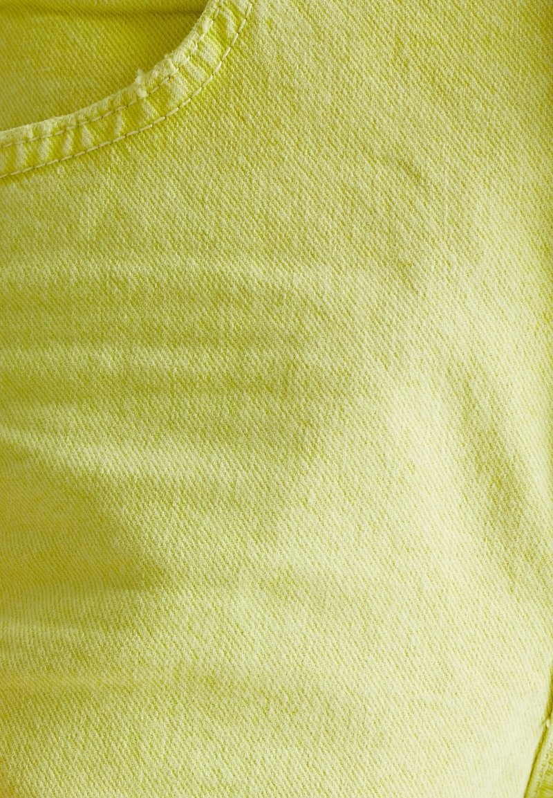 Limoengroen stof met een gestructureerd oppervlak en een ronde halslijn. Gestikte zoomdetails zijn zichtbaar langs de randen, wat de duurzaamheid verhoogt.