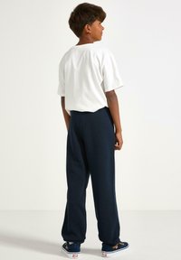 Hvid bomulds t-shirt med korte ærmer, parret med navy blå sweatpants. Sweatpantsene har en afslappet pasform og en elastisk talje.