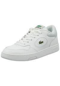 Bijele tenisice od glatke kože, s zelenim Lacoste logotipom, dizajnom na vezivanje, podstavljenim okomitim dijelom i teksturiranom gumom.