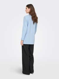 Light blue long-sleeve top with a relaxed fit, paired with loose-fitting black pants. Simple design, smooth texture, no visible patterns.