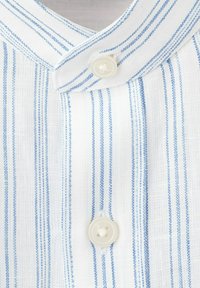 Tissu blanc à rayures verticales bleu clair, présentant un gros plan sur un col boutonné avec deux boutons ronds blancs.