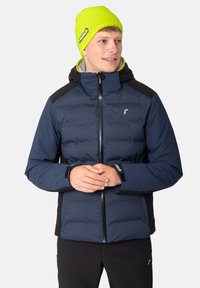 Blue insulated jacket with black accents, zippered front, and hood. Man wearing a bright yellow knit beanie. Smooth fabric texture.