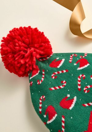 Green knitted beanie with red pom-pom, featuring white candy canes and red Santa hats in a repeating pattern. Smooth texture, festive design.