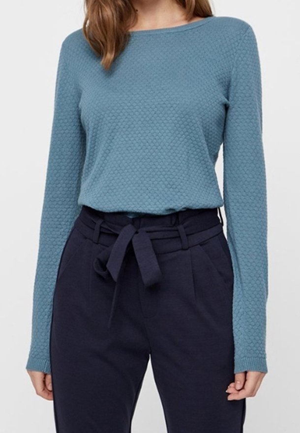 Haut à manches longues texturé couleur sarcelle avec un col rond, associé à un pantalon taille haute bleu marine foncé avec ceinture à nouer et poches.