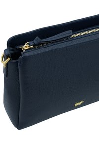 Pochette in pelle blu navy con finitura testurizzata, caratterizzata da una cerniera e dettagli in metallo dorato. Forma rettangolare compatta, progettata per una facile maneggiabilità.