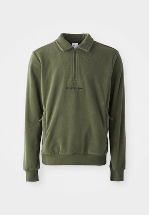 Olivgrüner Fleece-Pullover mit einem halben Reißverschluss, versehen mit einem "PARIS"-Logo und dem Nike-Swoosh. Seitentaschen und gerippte Bündchen runden das Design ab.