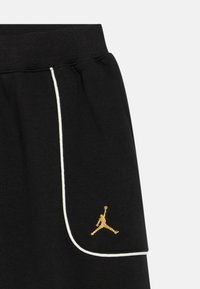 Črne atletske kratke hlače z belim obrobjem, z zlatim vezenim Jumpman logotipom na levi strani. Mehka bombažna mešanica.