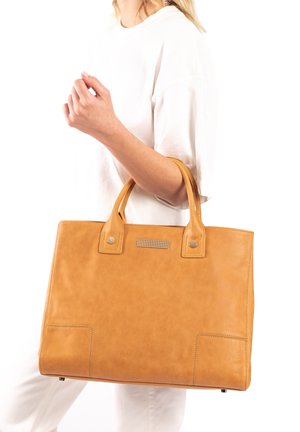Tote bag van bruin leer met gestikte accenten, twee bovenhandvaten en een metallic versiering aan de voorkant. Glad oppervlak en rechthoekige vorm.
