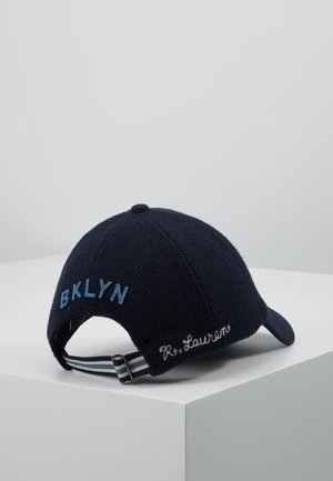 Navyblå baseballkasket med "BKLYN" broderet i lyseblåt bagpå og "R. Lauren" syet i hvidt nær den justerbare stribede rem.