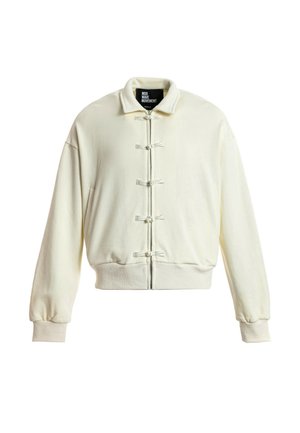 Chaqueta off-white con cremallera, cuello ancho, puños y dobladillo acanalados, con cinco cierres decorativos en forma de nudos de tela en la parte delantera.