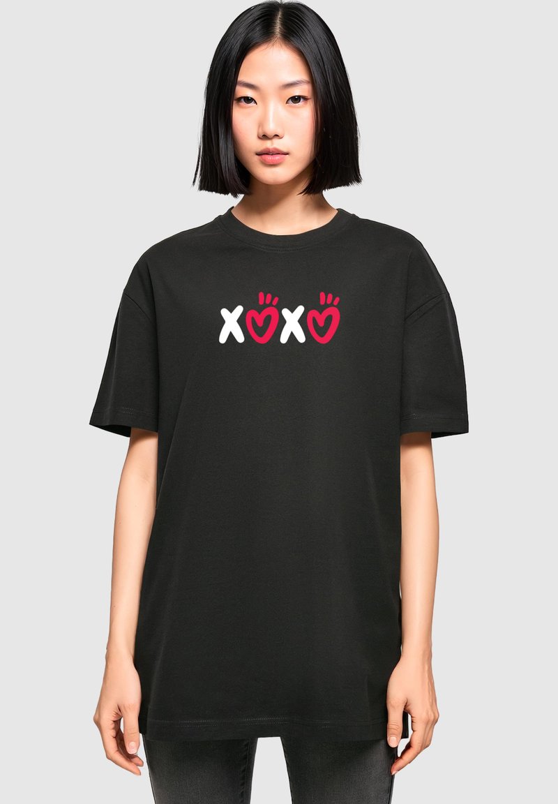 Tricou din bumbac negru, cu un grafic frontal ce prezintă textul "XOXO" în alb și roșu, alături de desene cu inimi, într-un croi relaxat.