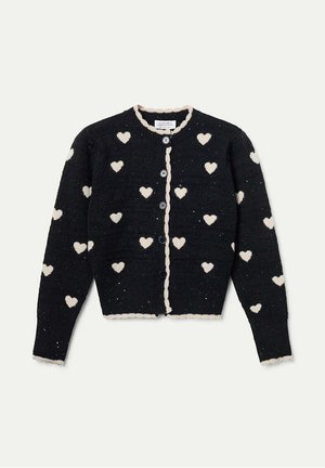 Cardigan de punto negro con patrones de corazones blancos, bordes ondulados y cuatro botones en la parte delantera. Tejido texturizado con manchas ligeras.