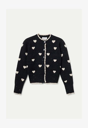 Cardigan de punto negro con patrones de corazones blancos, bordes ondulados y cuatro botones en la parte delantera. Tejido texturizado con manchas ligeras.