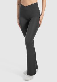 Høj-højdede sorte flared leggings lavet af strækbart stof med en glat tekstur og en korset-talje design.