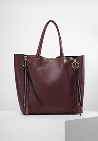 Sac cabas bordeaux en cuir texturé, avec deux poignées robustes, des fermetures éclairs latérales et des accents noirs pour plus de détails. Forme rectangulaire.