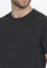 Mörkgrå t-shirt med rund hals och korta ärmar, tillverkad av lättviktig tyg. Har en subtil texturerad mönster och en svag logotyp på bröstet.