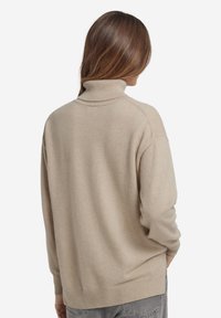 Maglione beige a collo alto con vestibilità ampia, polsini e orlo a coste. Tessuto morbido, lavorato a maglia, con spalle scese.