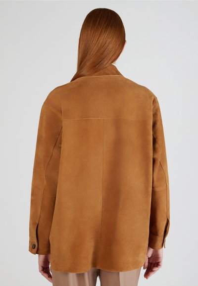 Veste en daim marron avec une coupe décontractée, grand col, fentes latérales et poignets boutonnés. Texture lisse et détails de couture minimalistes.