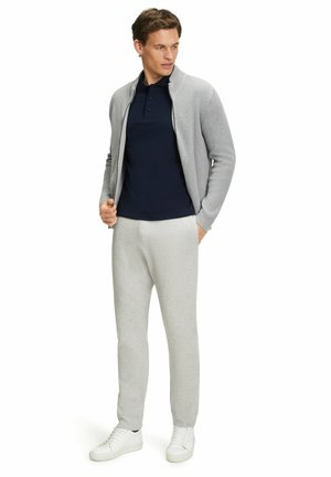 Light gray ribbed cardigan, navy polo, gray sweatpants, and white sneakers. The outfit features a relaxed fit and casual style.