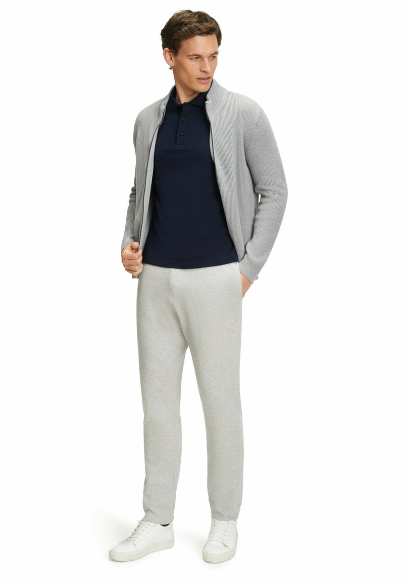 Jasnoszary kardigan w prążki, granatowy polo, szare dresy i białe sneakersy. Strój charakteryzuje się luźnym krojem i swobodnym stylem.