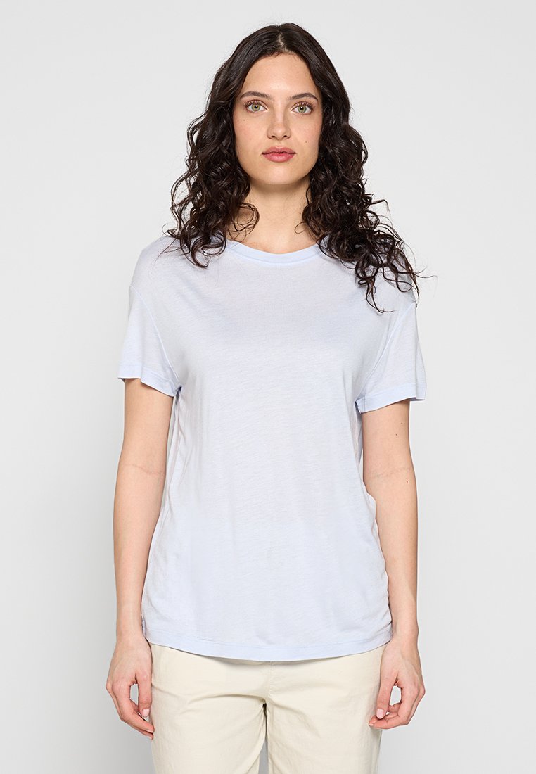 Helles blaues T-Shirt aus weicher Baumwolle. Mit Rundhalsausschnitt und kurzen Ärmeln in lockerer Passform. Glatte Textur, minimalistisches Design.