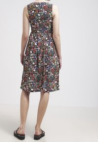 Blumendruckkleid mit schwarzem Hintergrund, ärmellosem Design, tailliertem Mittelteil und knielangem Rock. Akzentuiert mit verschiedenfarbigen Blumen.
