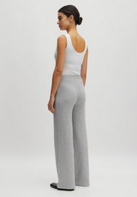 White ribbed tank top with a scooped back, paired with gray wide-leg knitted pants featuring a vertical rib pattern. Smooth fabric texture.