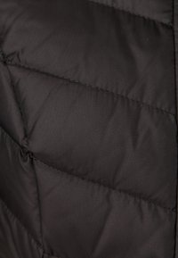 Tessuto di giacca trapuntata nera con trama trapuntata, caratterizzata da cuciture orizzontali e una finitura liscia e lucida.