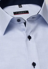 Kurzarmhemd in Hellblau mit dezentem Karomuster, schwarzen Knöpfen, kontrastierendem marineblauen Kragen und dem Label "ETERNA MODERN FIT".