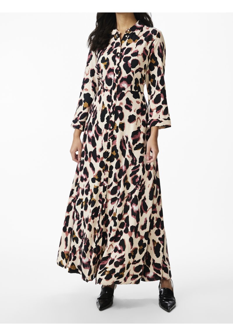Robe longue avec un imprimé léopard aux tons beige, noir, rose et or. Manches longues, boutons sur le devant, fentes latérales. Texture de tissu lisse.
